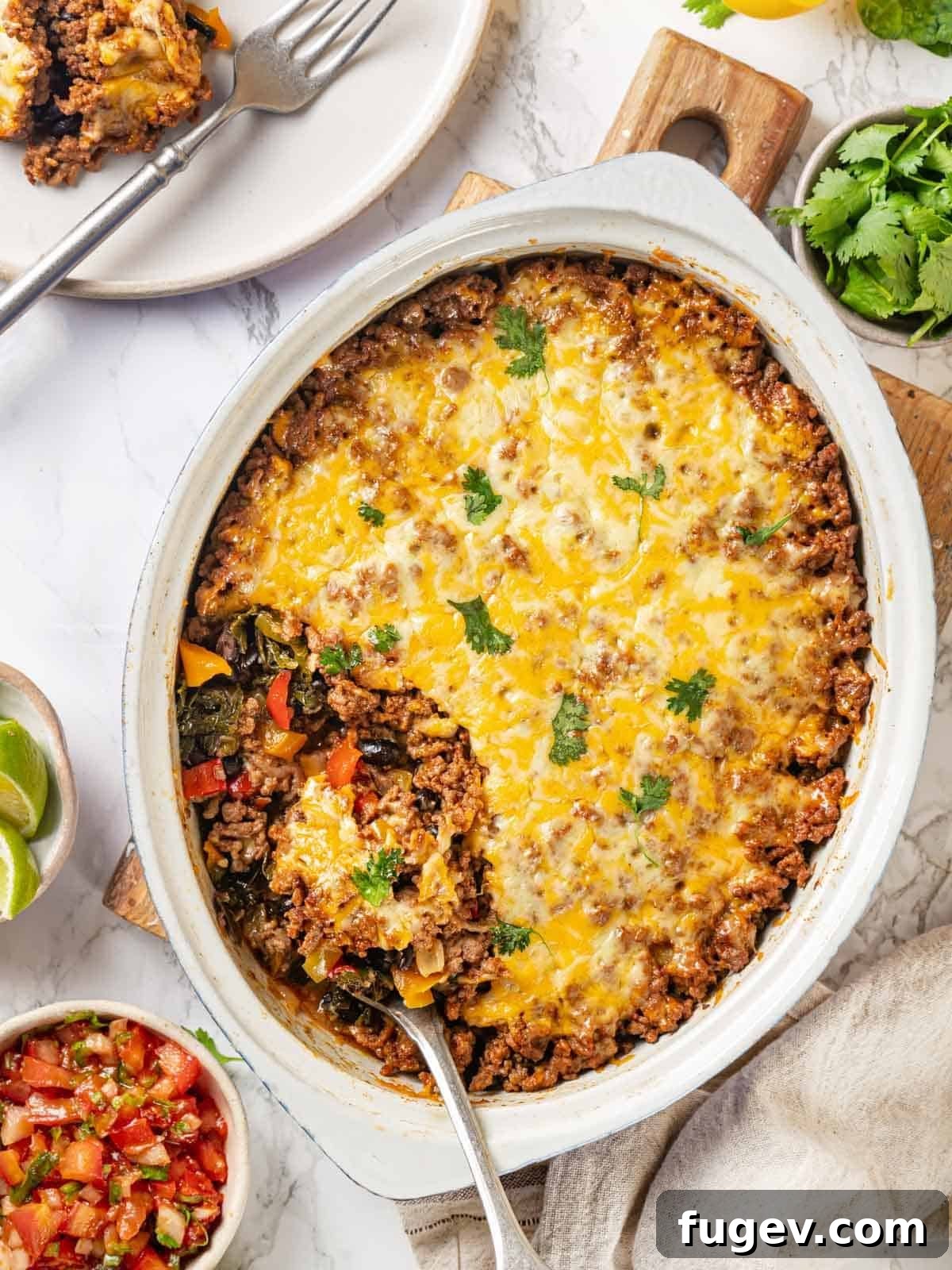 Cheesy Taco Bake 14 A white serving dish filled with the healthy taco bake, ready to be served with a silver spoon.