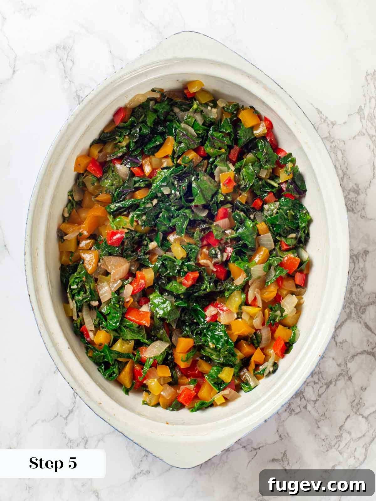 Cheesy Taco Bake 9 Adding cooked bell peppers, onions, and kale to a white casserole dish.