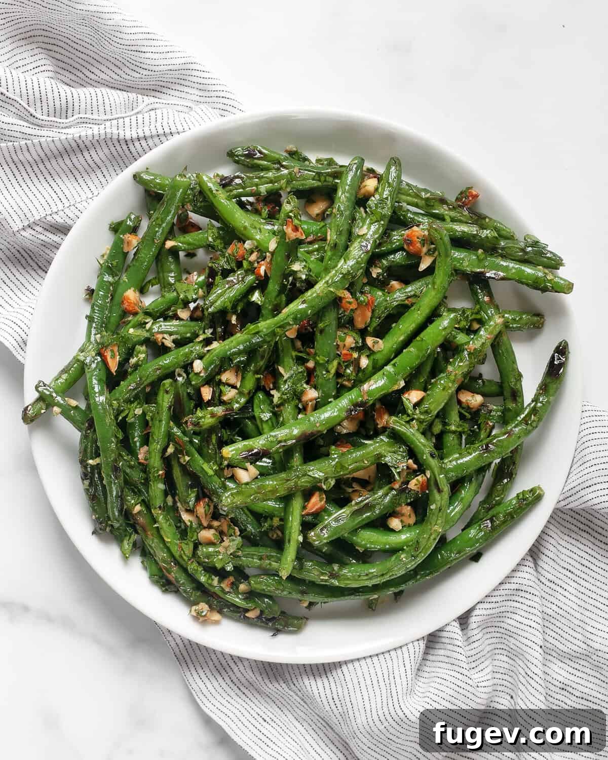 Smoky Green Beans with Bright Almond Gremolata 2 Grilled green beans with almond gremolata on a plate, ready to be served as a delightful summer side.