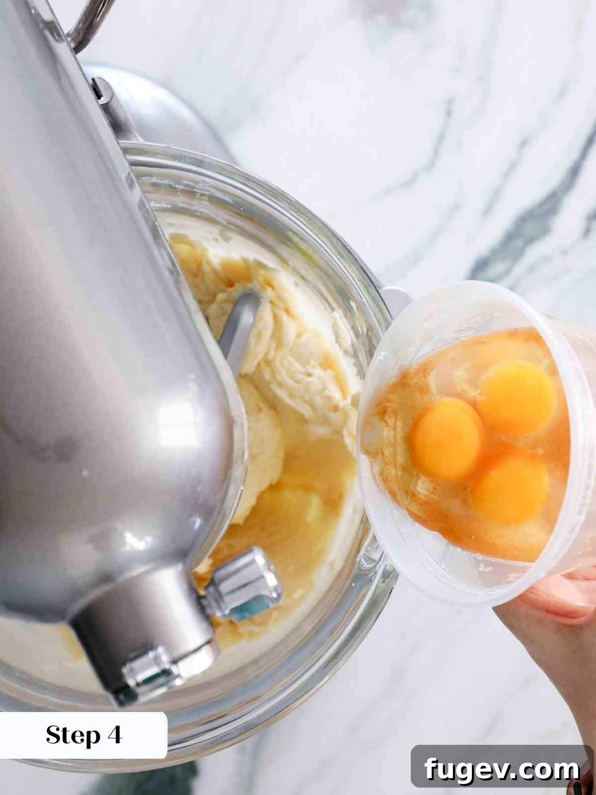Velvet Vanilla Cake Recipe 12 Adding eggs one by one to the creamy cake batter for perfect emulsification.