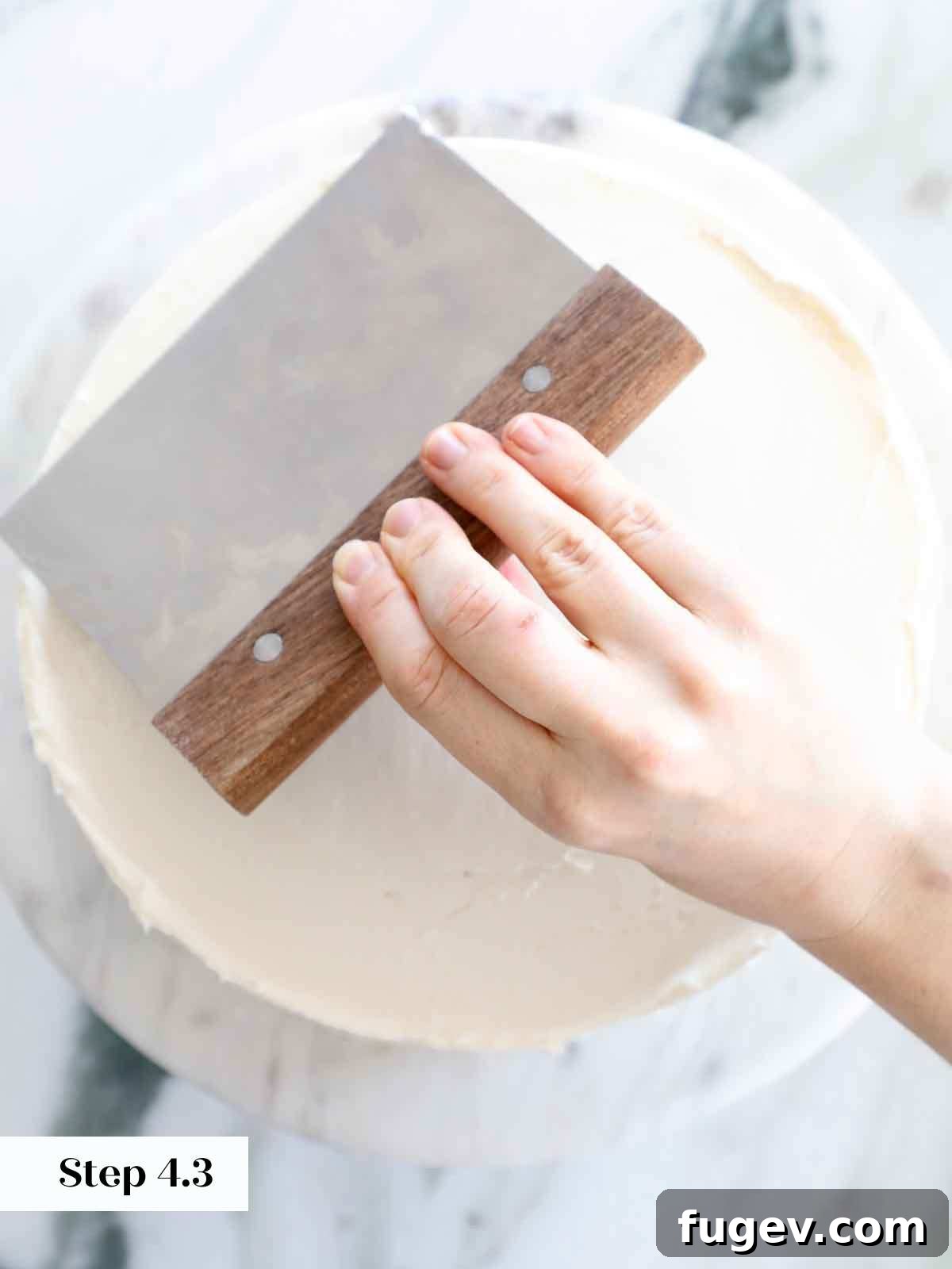 Velvet Vanilla Cake Recipe 25 A large offset spatula smoothing the top of a vanilla cake with buttercream to a flawless finish.