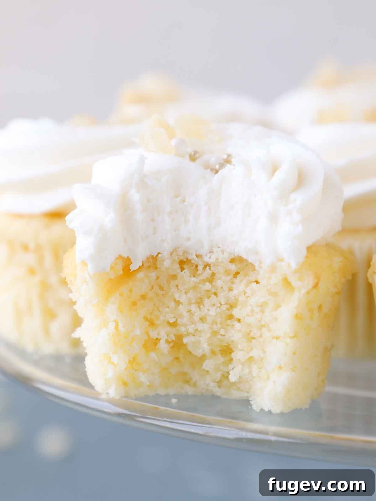 Zesty Lemon Delights 6 interior texture of lemon cupcake on clear cake stand and blue surface.