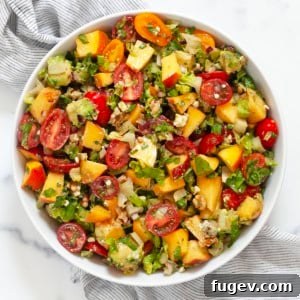 Chopped salad with peaches and tomatoes in a bowl.
