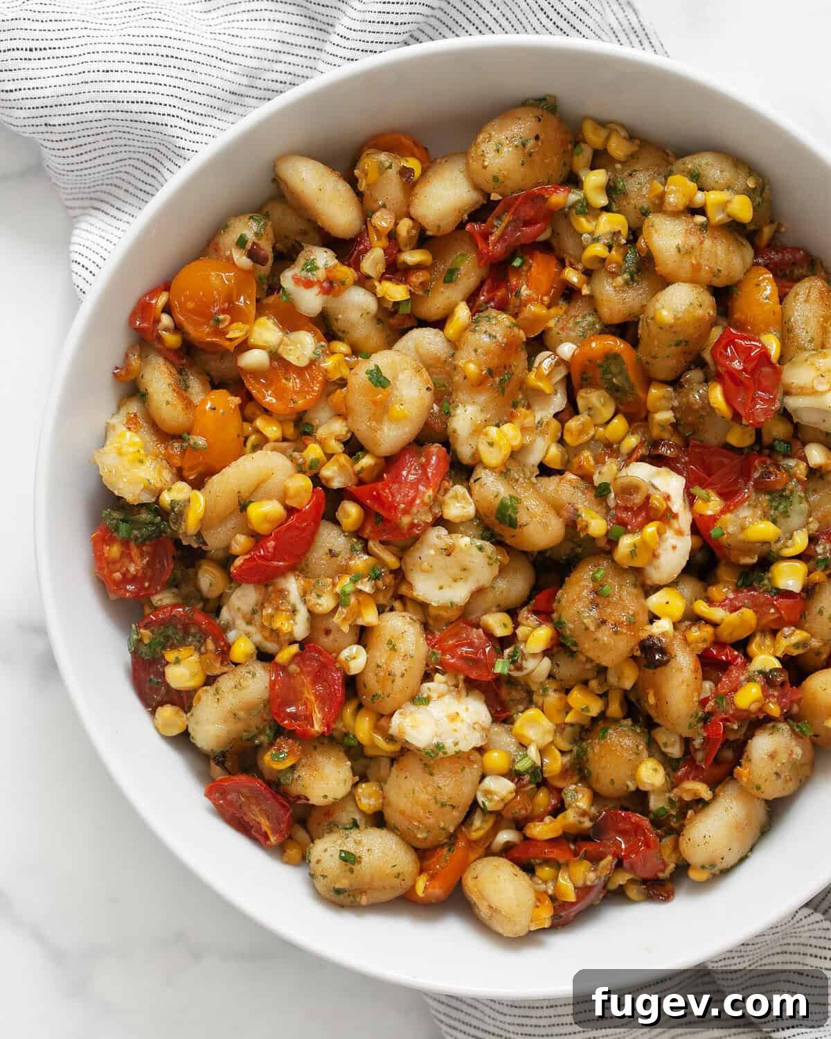 Roasted Gnocchi with Burst Tomatoes and Sweet Corn 2 Sheet pan gnocchi with tomatoes and corn in a bowl, ready to be served as a delightful summer vegetarian dinner.