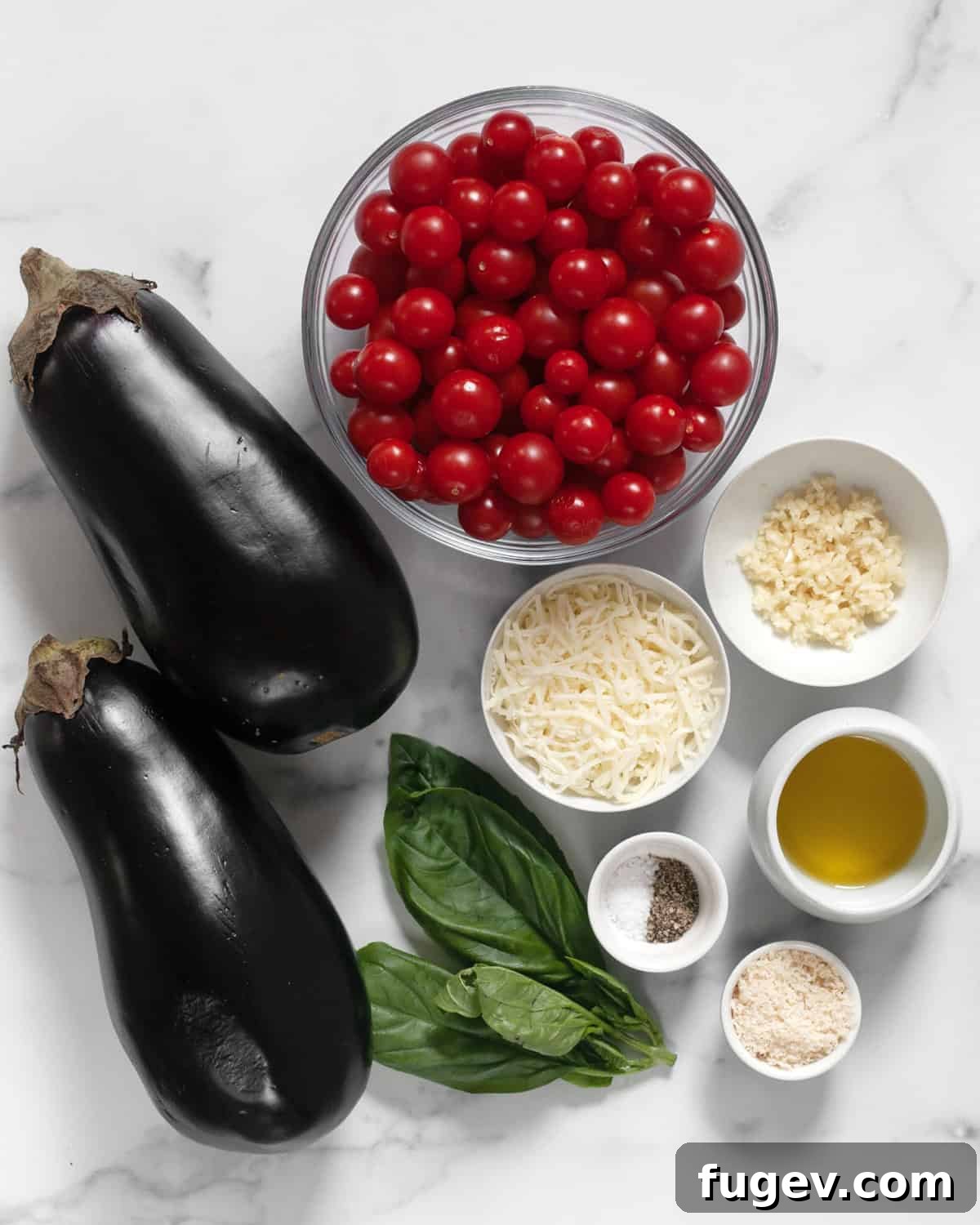 Savory Eggplant Gratin 3 Assorted fresh ingredients for eggplant casserole arranged on a cutting board, including eggplants, cherry tomatoes, fresh basil, shredded cheese, grated parmesan, garlic, olive oil, salt and pepper.