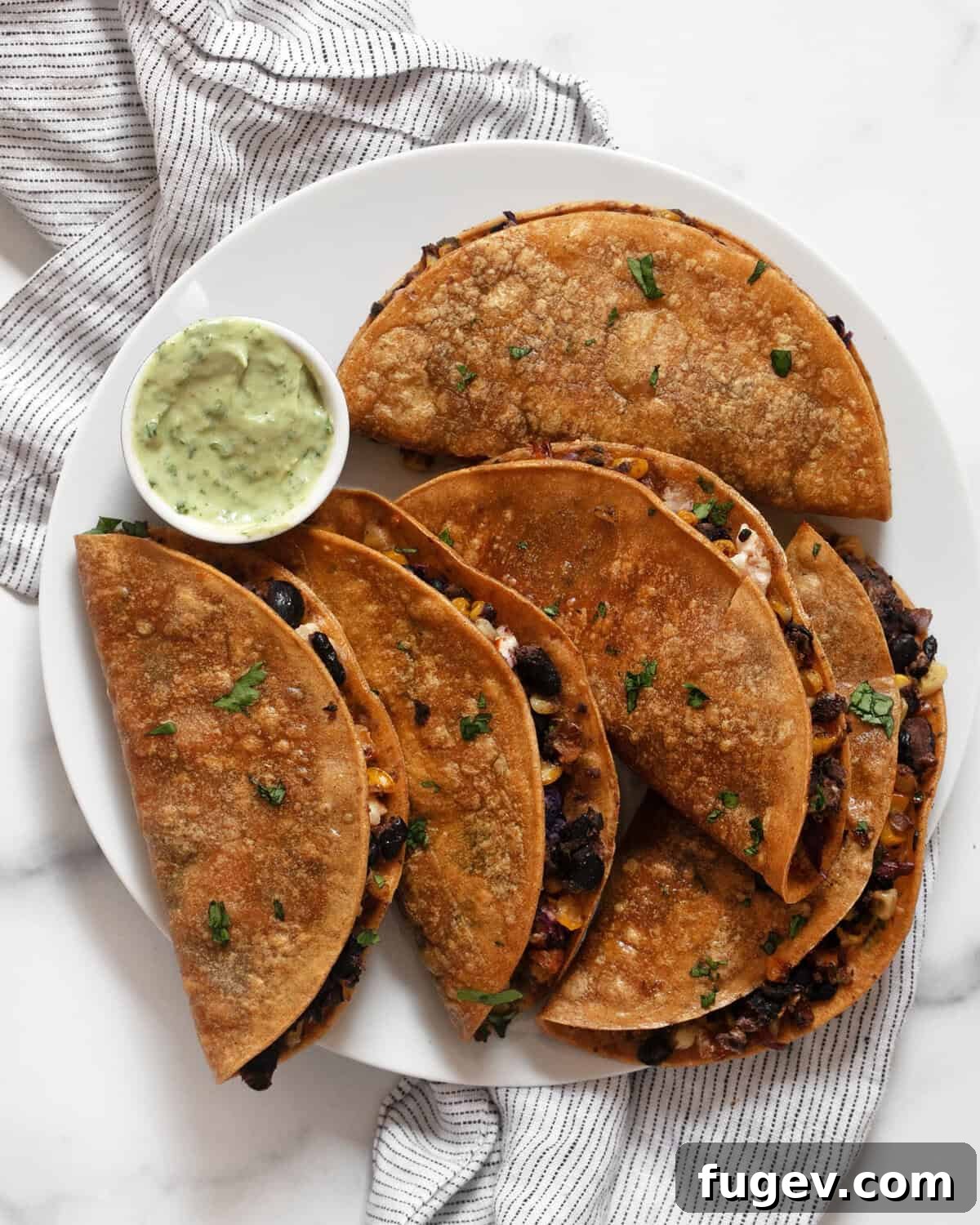 Crispy corn tacos on a plate, garnished with fresh cilantro and served with avocado crema.