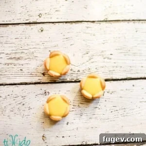 Three tiny, perfectly crafted lemon tartlets arranged on a clean white surface.