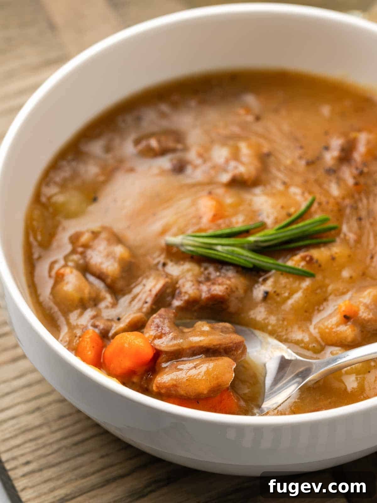Hearty Lamb Stew 2 Rich lamb stew served on a spoon, garnished with a fresh rosemary sprig, promising warmth and flavor.