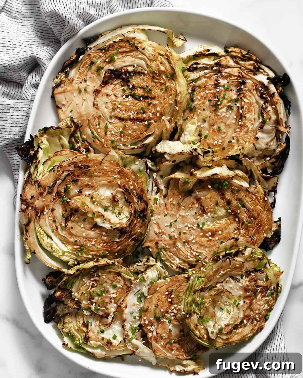 Smoky Grilled Cabbage Steaks 2 Grilled cabbage steaks artfully arranged on a serving platter, garnished with fresh herbs and sesame seeds.
