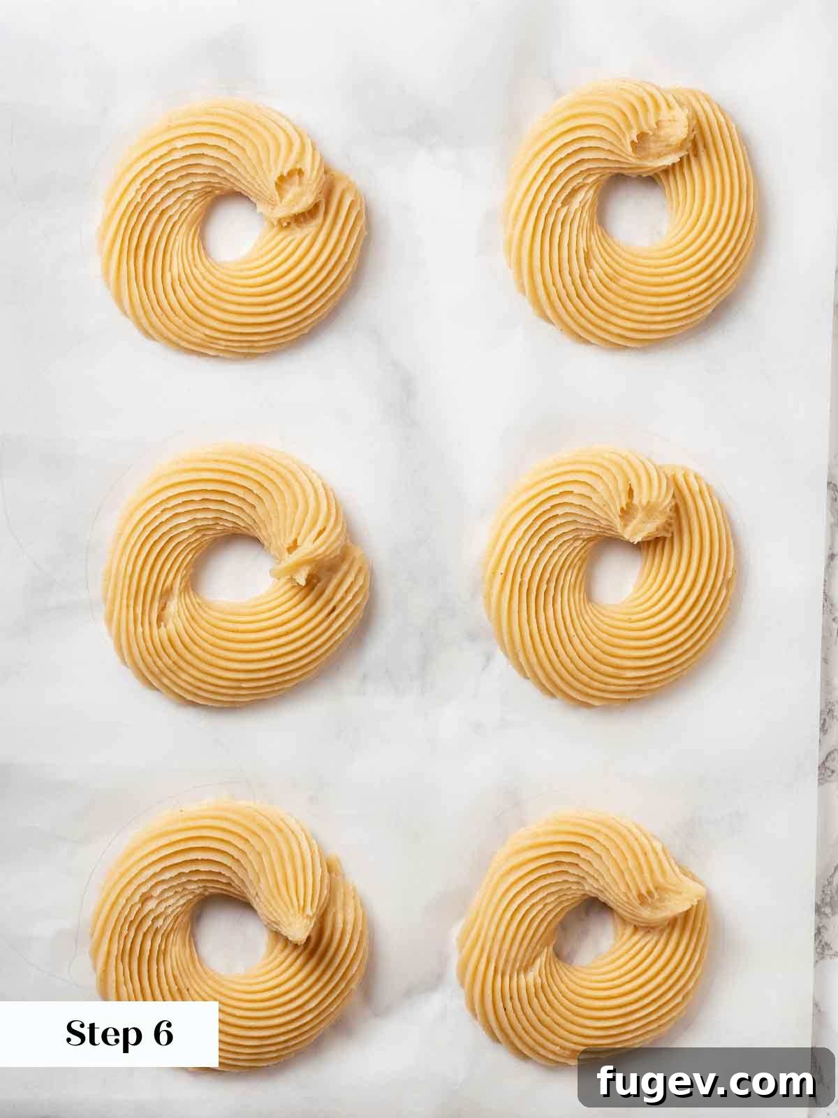 Elegant Choux Doughnuts 13 piped cruller dough on parchment paper.