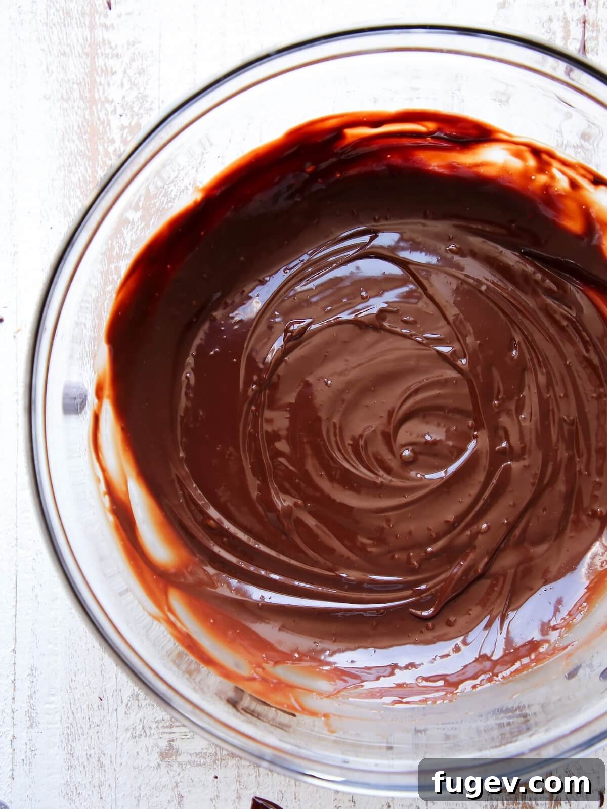 Mastering Chocolate Ganache 10 A bowl of perfectly shiny and smooth chocolate ganache, reflecting light beautifully.