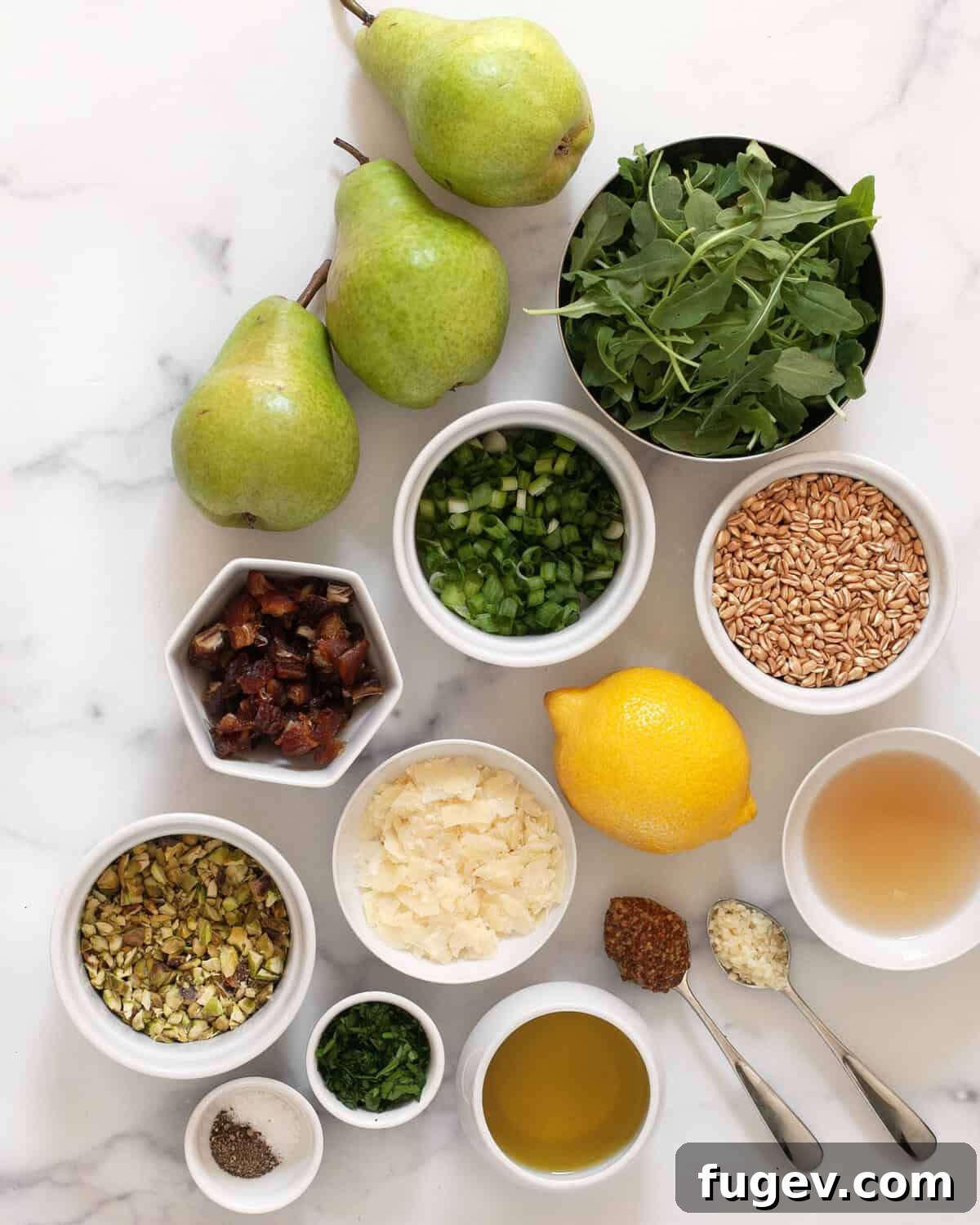 Sweet Pear and Hearty Farro Salad 3 A curated display of fresh ingredients for pear farro salad, including whole pears, uncooked farro, fresh arugula, dates, pistachios, parmesan, lemon, olive oil, garlic, and mustard.