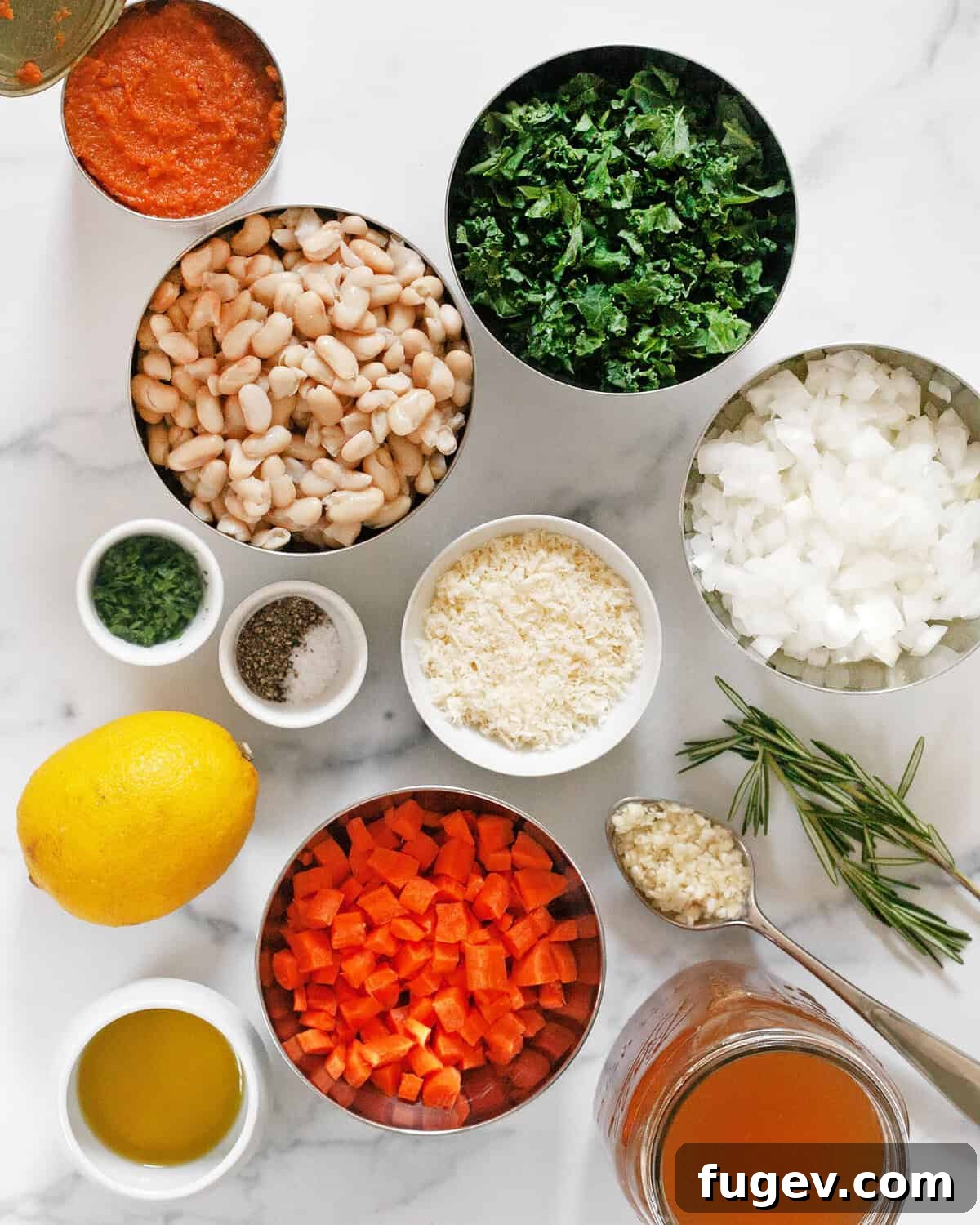 Velvety Pumpkin Soup with Cannellini Beans and Kale 3 A flat lay photograph showcasing all the ingredients for creamy pumpkin soup: canned pumpkin puree, white beans, kale, onions, parmesan, carrots, lemon, garlic, rosemary, vegetable broth, olive oil, salt, pepper, and fresh parsley.