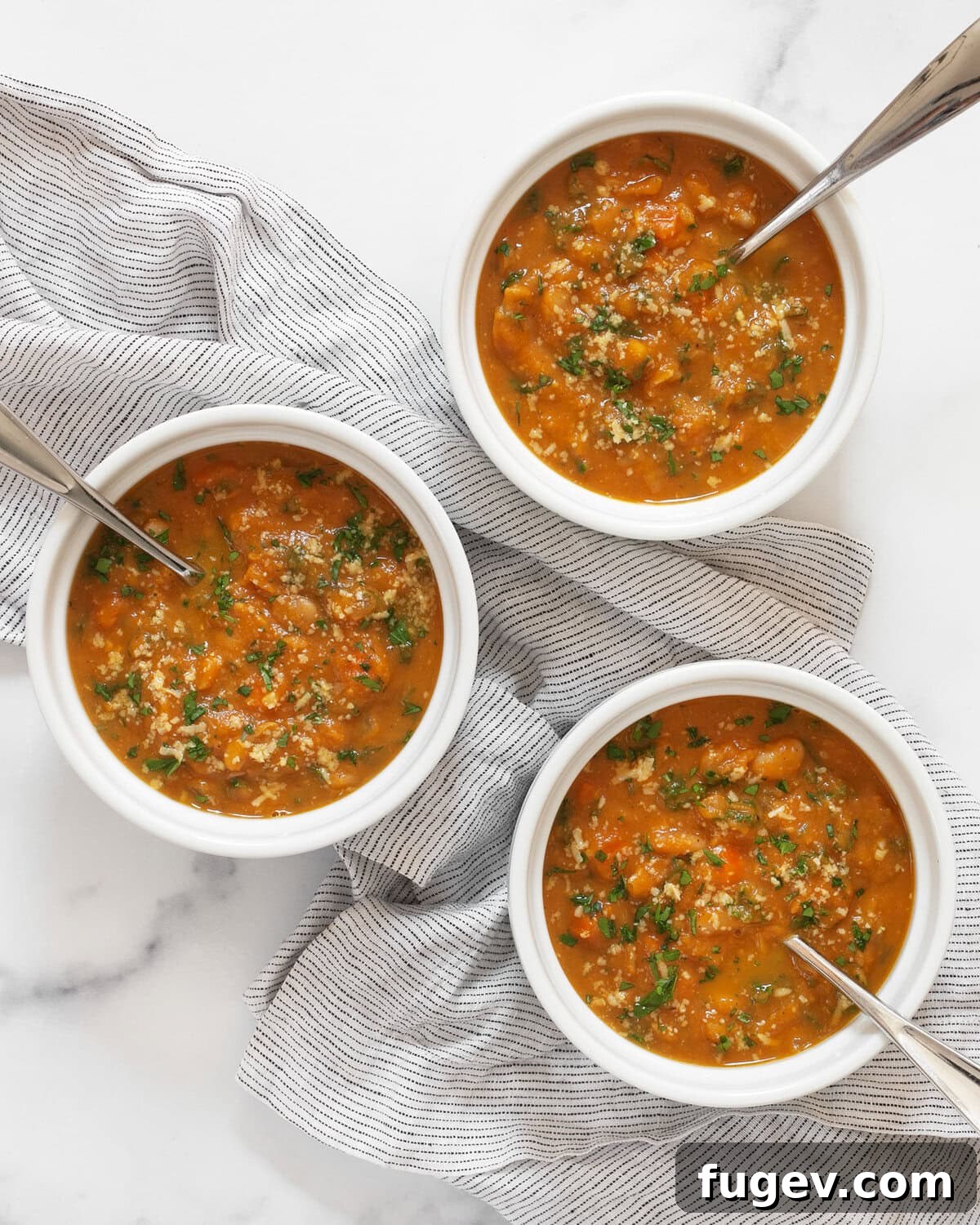 Velvety Pumpkin Soup with Cannellini Beans and Kale 7 Three bowls of creamy pumpkin soup, ready to be served.