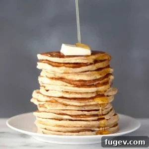 Stacked whole-wheat buttermilk pancakes with melted butter and syrup.