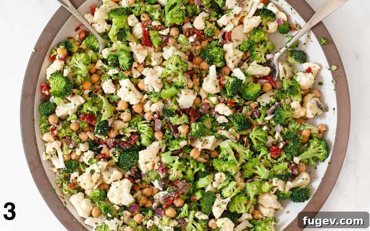 Garden Crisp Florets Salad 5 Broccoli cauliflower salad ingredients tossed with the tahini vinaigrette in a large bowl, showing a perfectly dressed and mixed salad.