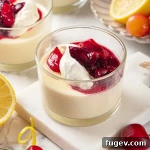 Three lemon possets in glasses, garnished with whipped cream and cherry sauce.