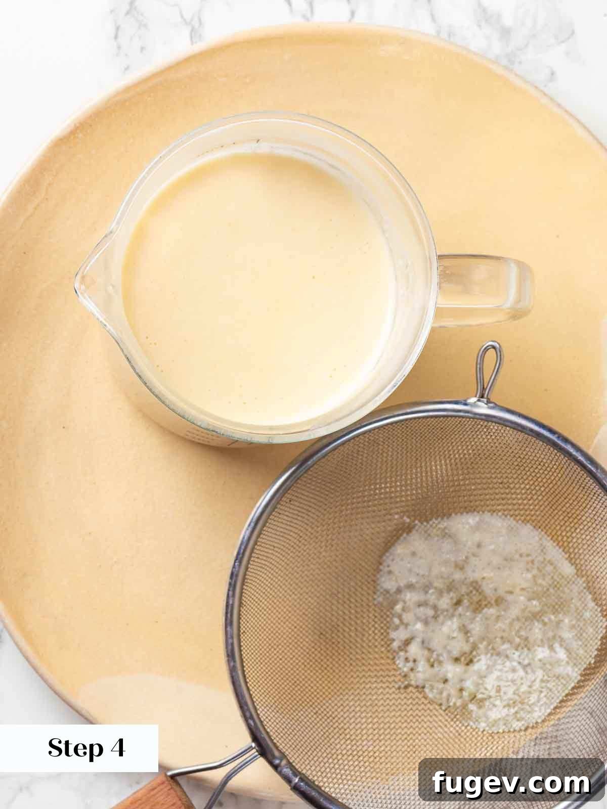Zesty Lemon Cream 8 Lemon posset mixture being strained through a fine-mesh sieve into a measuring cup with a spout, ensuring a perfectly smooth texture and easy pouring.