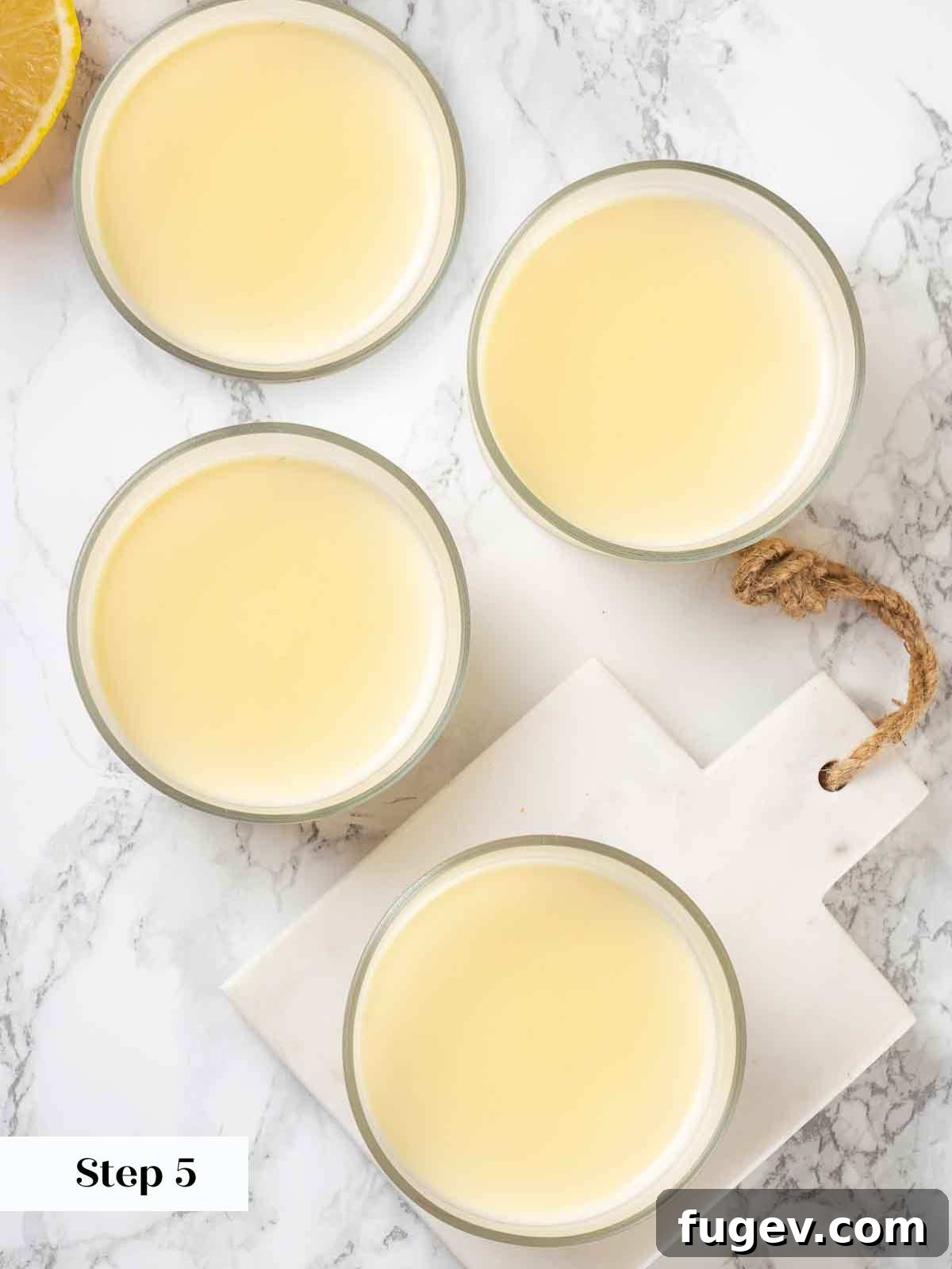 Zesty Lemon Cream 9 Strained lemon posset mixture divided into small serving glasses, being placed into the refrigerator for chilling until firm.