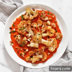 Roasted cauliflower steaks with roasted red pesto on a plate.