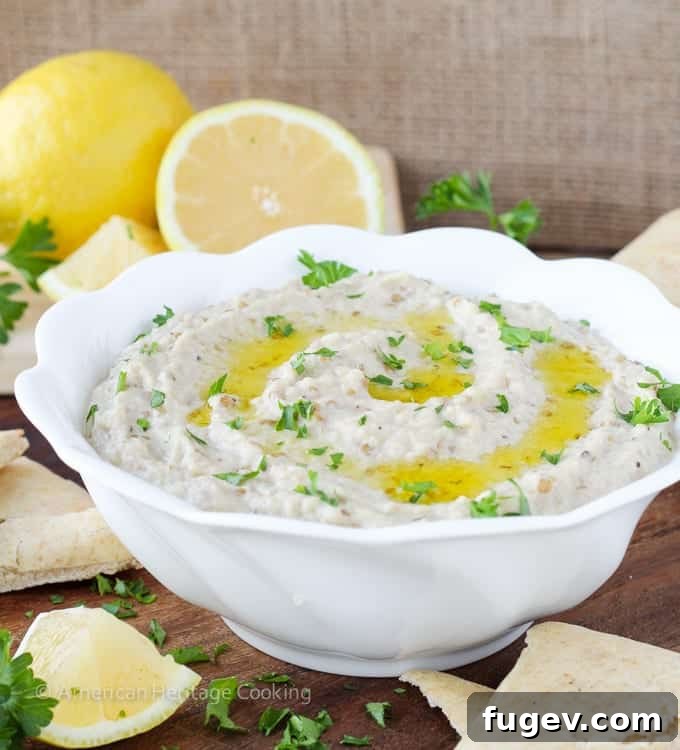 Smoky Eggplant Dip 6 A vibrant platter featuring a generous serving of Baba Ganoush, alongside fresh cucumber and carrot sticks, cherry tomatoes, and various pita bread options.