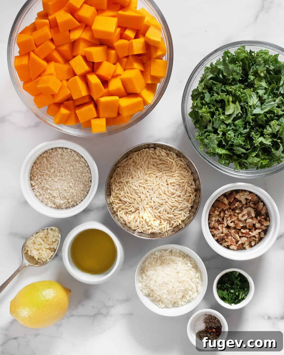 Golden Roasted Butternut Kale Orzo 3 A flat lay image displaying all the fresh ingredients for the Roasted Butternut Squash Kale Orzo recipe, including squash, kale, orzo, breadcrumbs, garlic, parmesan, walnuts, lemon, olive oil, and various seasonings.