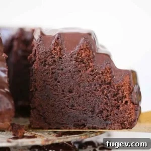 A close-up view of a chocolate bundt cake with a decadent ganache topping, showcasing its intricate design and dark, inviting color.