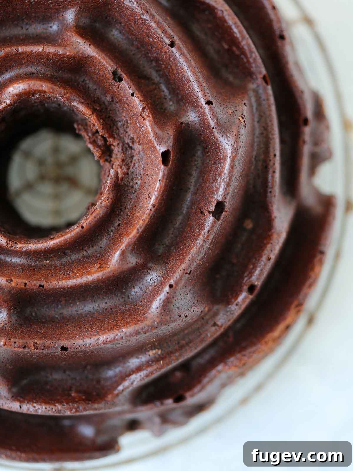 Decadent Chocolate Bundt 5 A simple, unadorned chocolate rose bundt cake, freshly released from its pan and cooling on a wire rack, showcasing its intricate floral design.