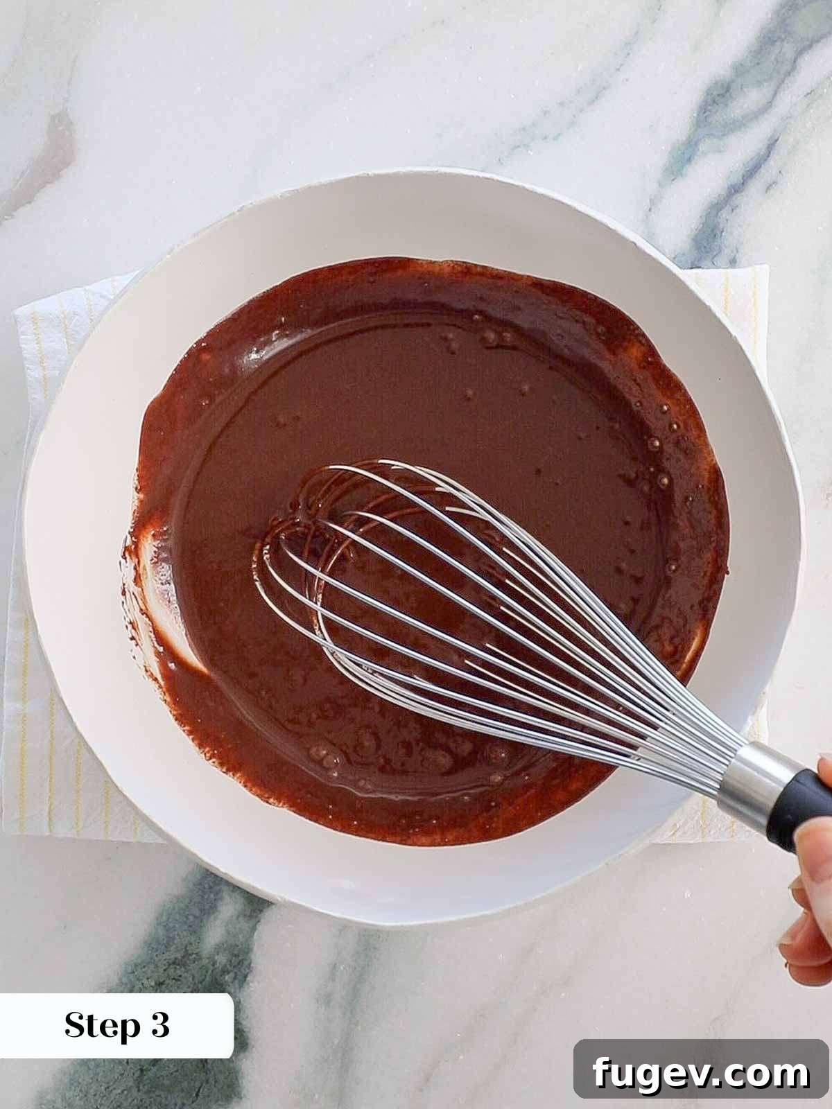 Decadent Chocolate Bundt 8 A whisk actively emulsifying a mixture of melted chocolate and cream, creating a glossy and smooth chocolate ganache.