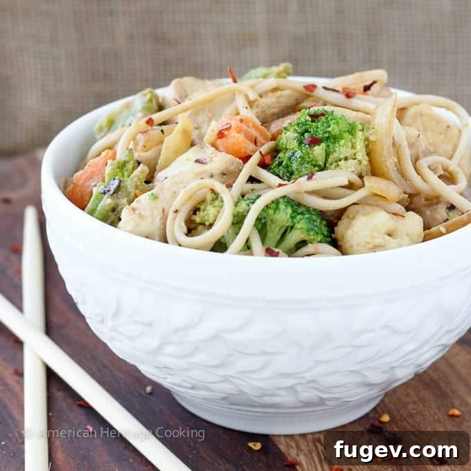 Creamy Thai Peanut Chicken Noodles 3 Close-up of Thai Peanut Chicken Noodle Stir Fry, showcasing the rich, glistening peanut sauce, tender chicken pieces, and vibrant mixed vegetables intertwined with udon noodles.