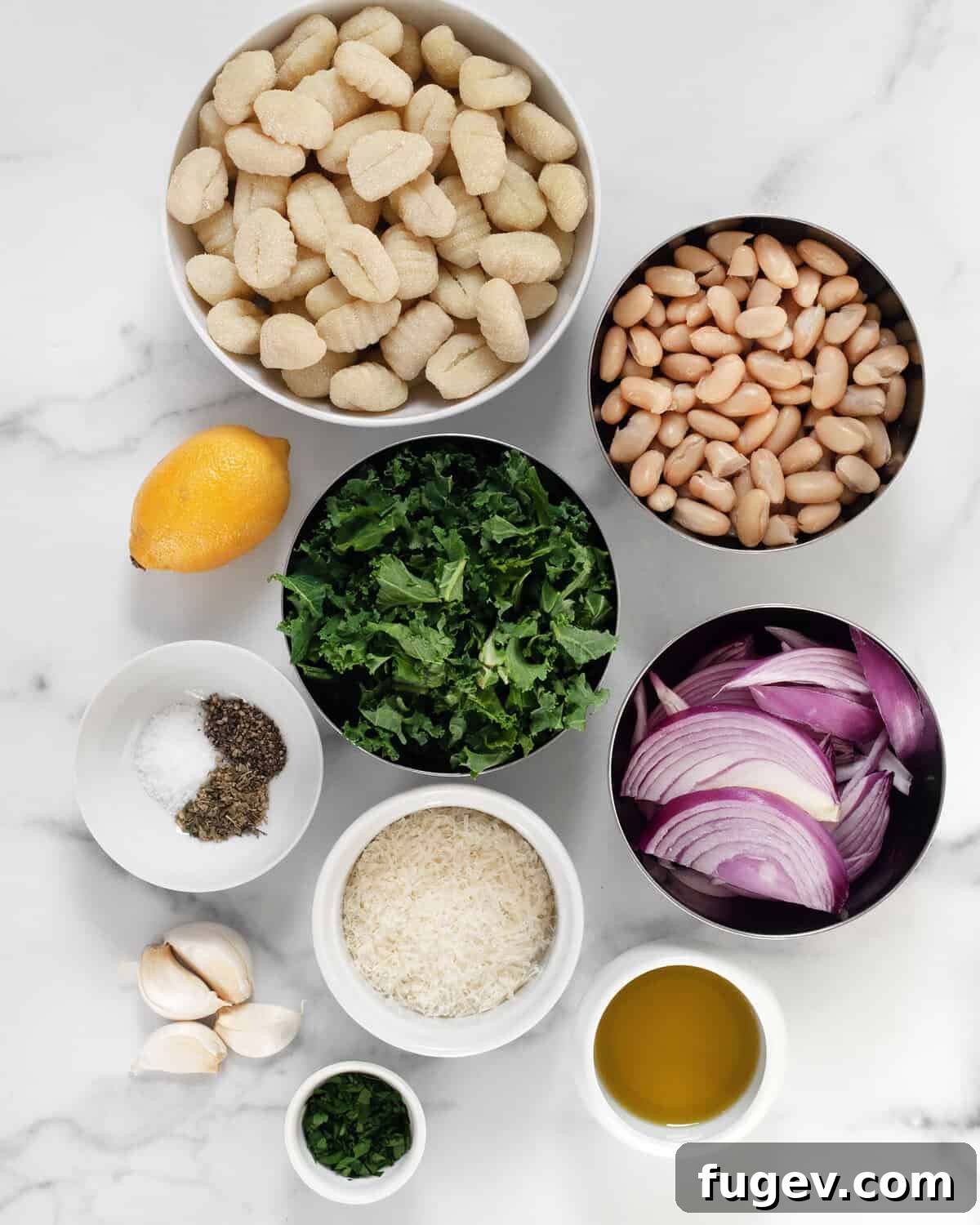 Effortless Sheet Pan Gnocchi, Beans and Kale 3 A vibrant flat lay of all the fresh ingredients for sheet pan gnocchi, including gnocchi, kale, cannellini beans, red onions, lemon, olive oil, and herbs.