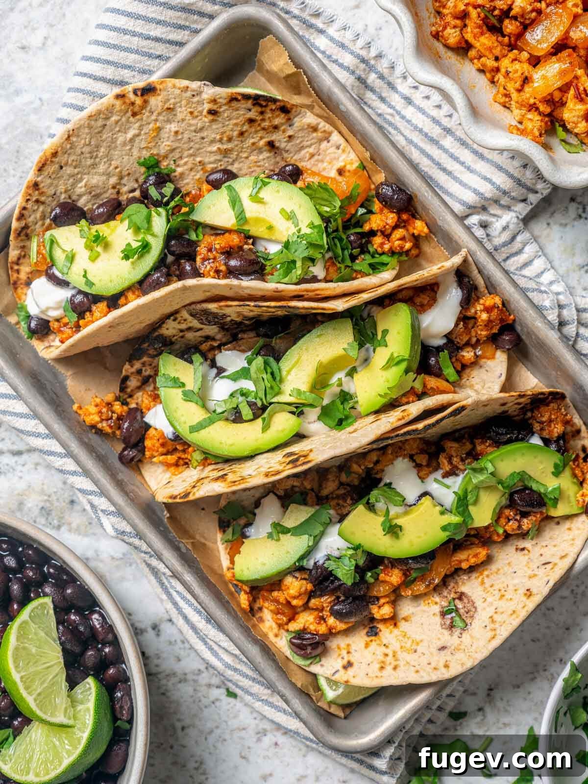 Zesty Ground Chicken Tacos 2 Three healthy ground chicken tacos in whole wheat tortillas, topped with avocado and cilantro, ready to eat.