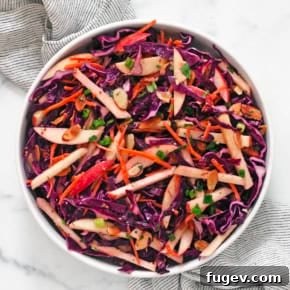 Vibrant Red cabbage salad with crisp apples, carrots, and toasted almonds, tossed in a creamy lemon tahini vinaigrette.