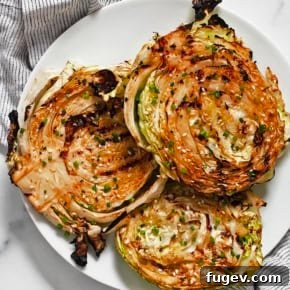 Smoky Grilled Cabbage Steaks with char marks, marinated in tahini, soy sauce, lime juice, ginger, and garlic.