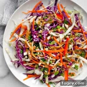 Colorful Asian Cabbage Salad with red and green cabbage, carrots, and red peppers, coated in a creamy almond ginger dressing.