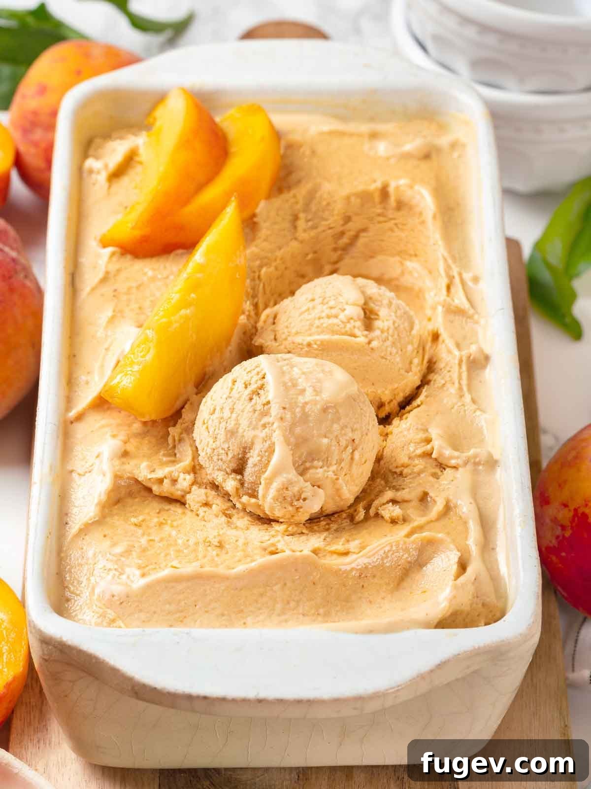 Luscious Peach Ice Cream 2 Scoops of fresh peach ice cream in a white loaf pan, garnished with fresh peach slices.