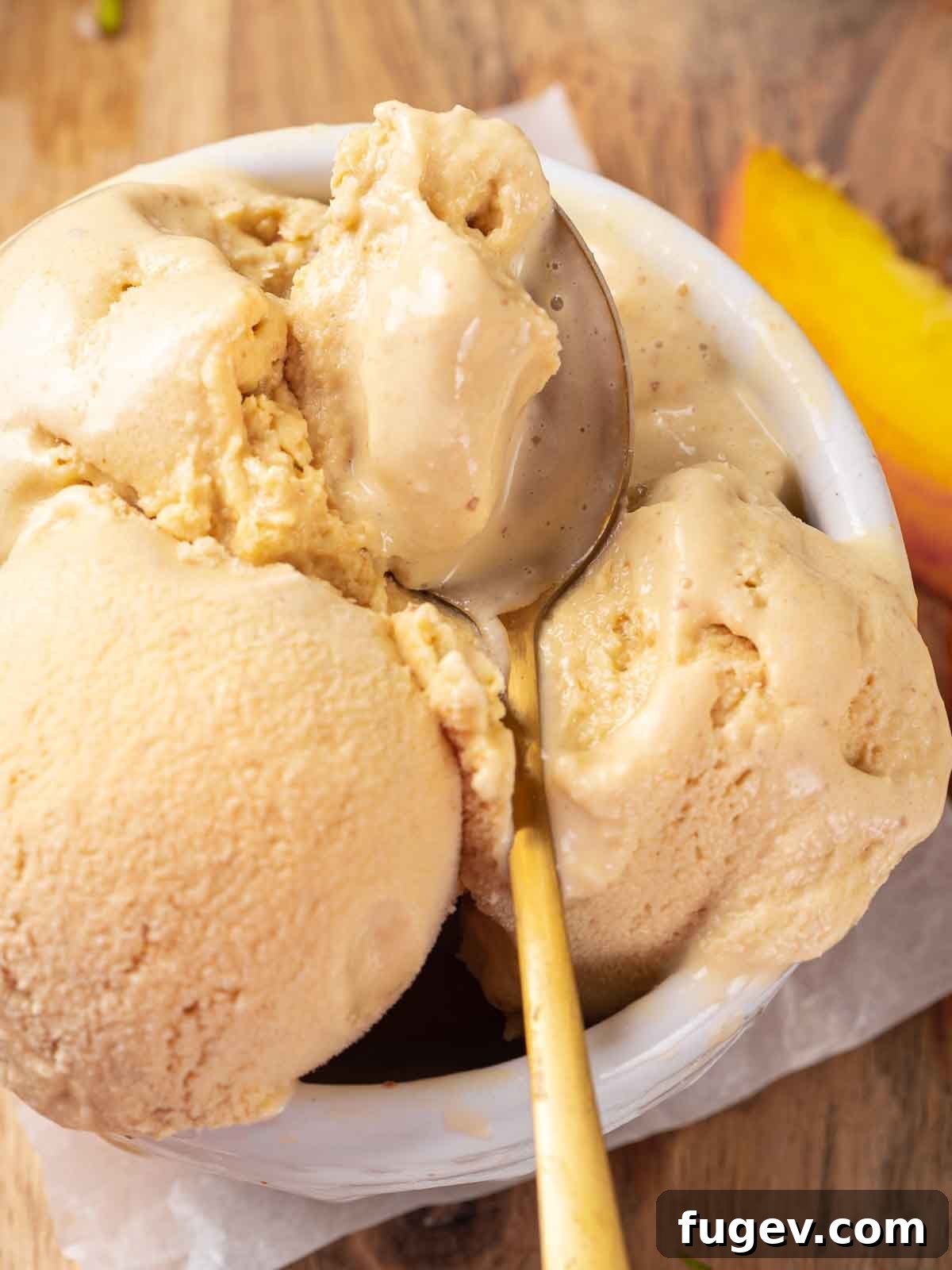 Luscious Peach Ice Cream 11 Scoops of fresh peach ice cream in a white bowl, with a gold spoon, ready to be enjoyed.