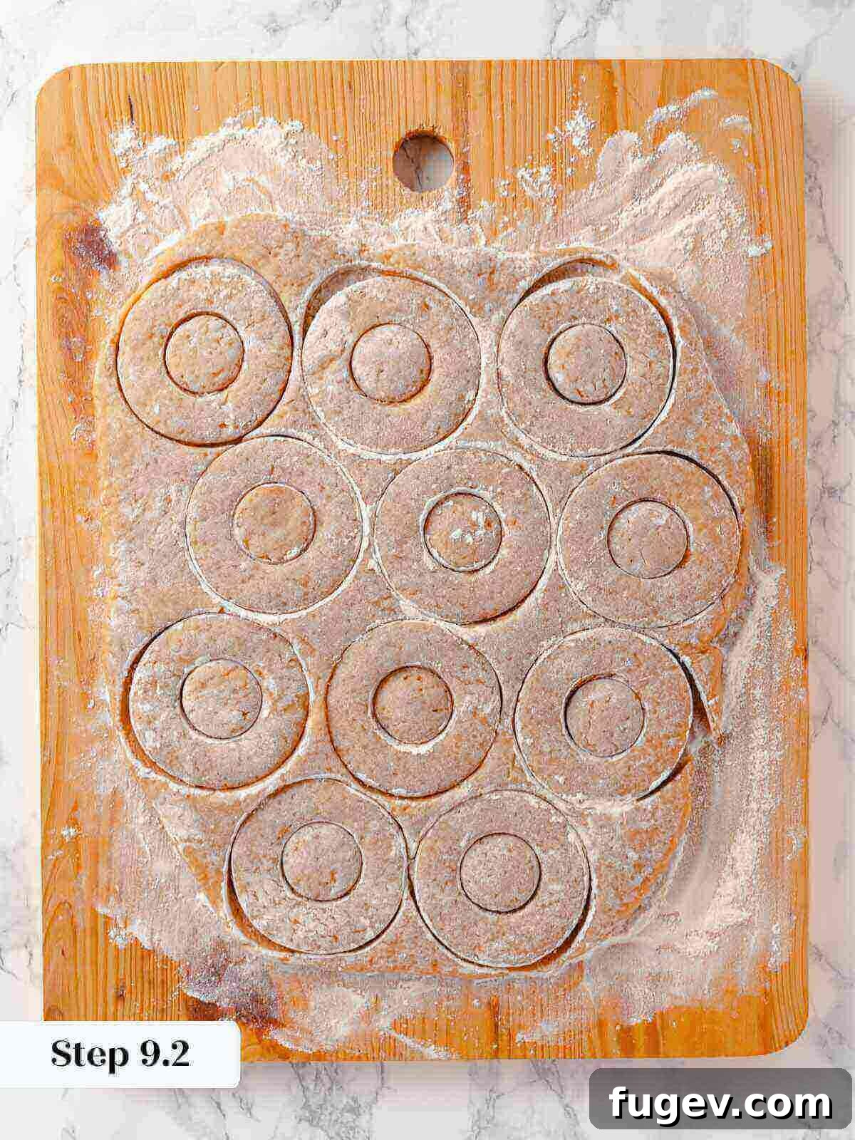 Harvest Apple Cider Donuts 16 Freshly cut apple cider donut dough shapes, including donut rings and holes, laid out on a floured surface.
