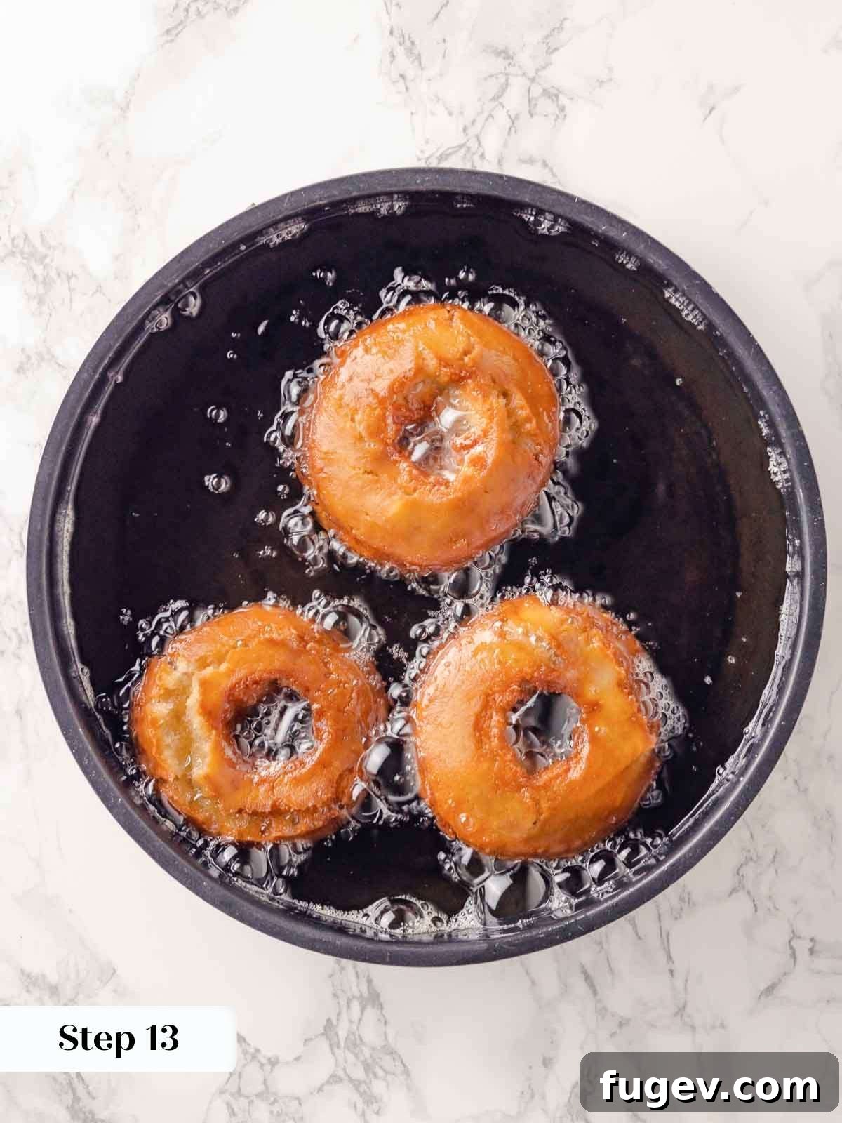 Harvest Apple Cider Donuts 19 Golden brown apple cider donuts frying in hot oil, bubbling as they cook to perfection.