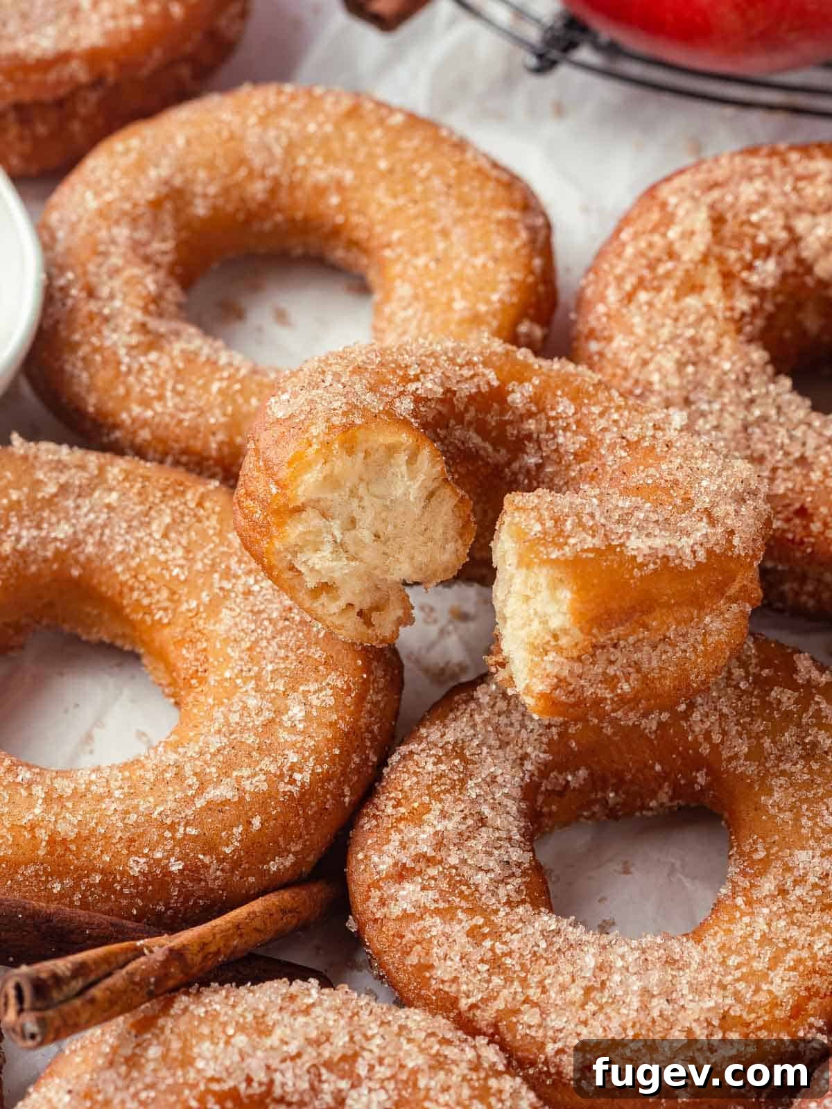 Harvest Apple Cider Donuts 20 A delightful group of freshly fried and sugared apple cider donuts resting on a cooling rack, highlighting their warm, inviting appearance.