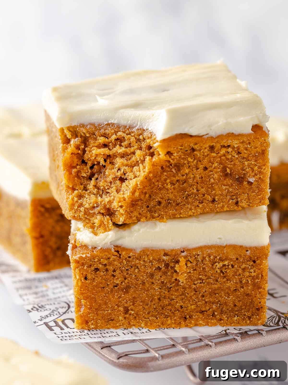 Autumn Pumpkin Spice Squares 2 A perfectly baked pumpkin bar, bitten to reveal its incredibly moist and tender interior, topped with a generous swirl of cream cheese frosting.