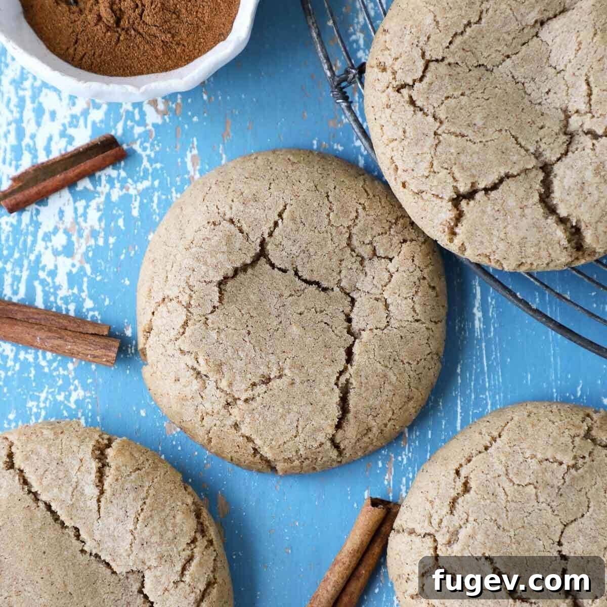 Sparkling Cinnamon Delights 3 Close-up photograph of a batch of cinnamon sugar cookies, showcasing their inviting golden-brown hue and beautifully crackled tops, cooling on a rack.
