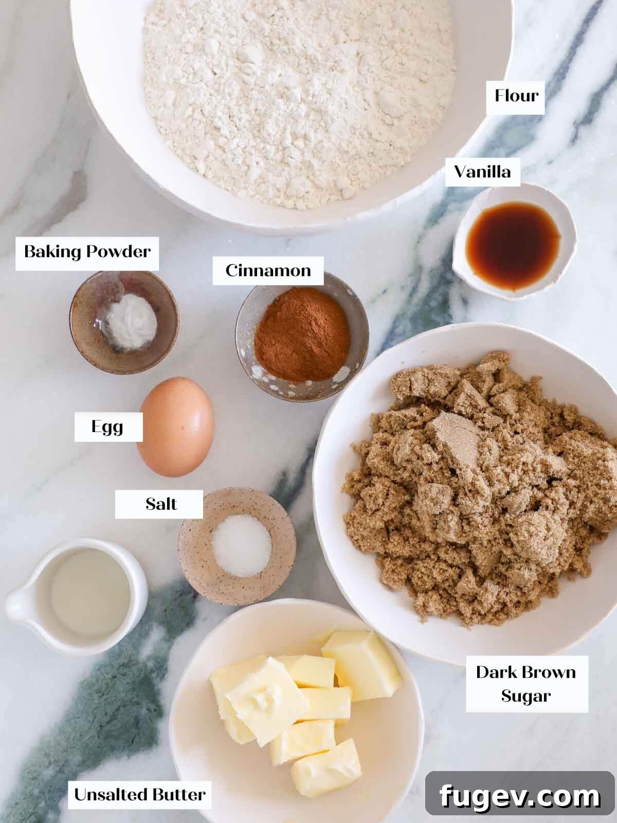 Sparkling Cinnamon Delights 4 A beautifully arranged selection of fresh ingredients for cinnamon sugar cookies, including dark brown sugar, unsalted butter, flour, and aromatic spices, all laid out on a clean white marble surface.