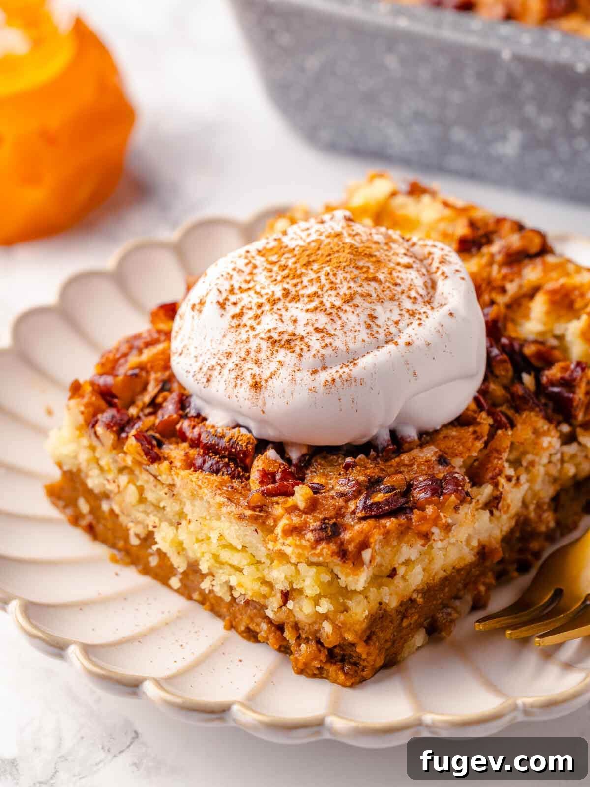 No-Fuss Pumpkin Dump Cake 2 A beautifully presented slice of pumpkin dump cake, served on a pristine white plate, garnished with a dollop of whipped cream and a sprinkle of cinnamon.