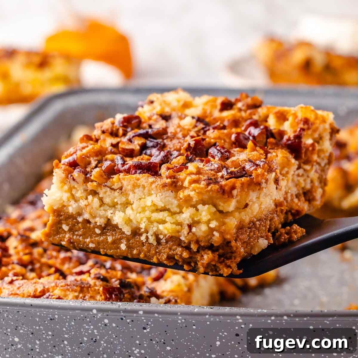 No-Fuss Pumpkin Dump Cake 4 A perfectly baked slice of pumpkin dump cake being carefully lifted from the baking pan with a serving spatula, showcasing its distinct layers and golden-brown topping.