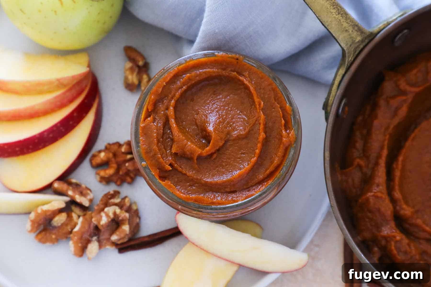 Cozy Spiced Pumpkin Butter 3 An inviting arrangement of nuts, dried fruits, and a jar of homemade pumpkin butter on a plate with a blue napkin, perfect for a fall spread.