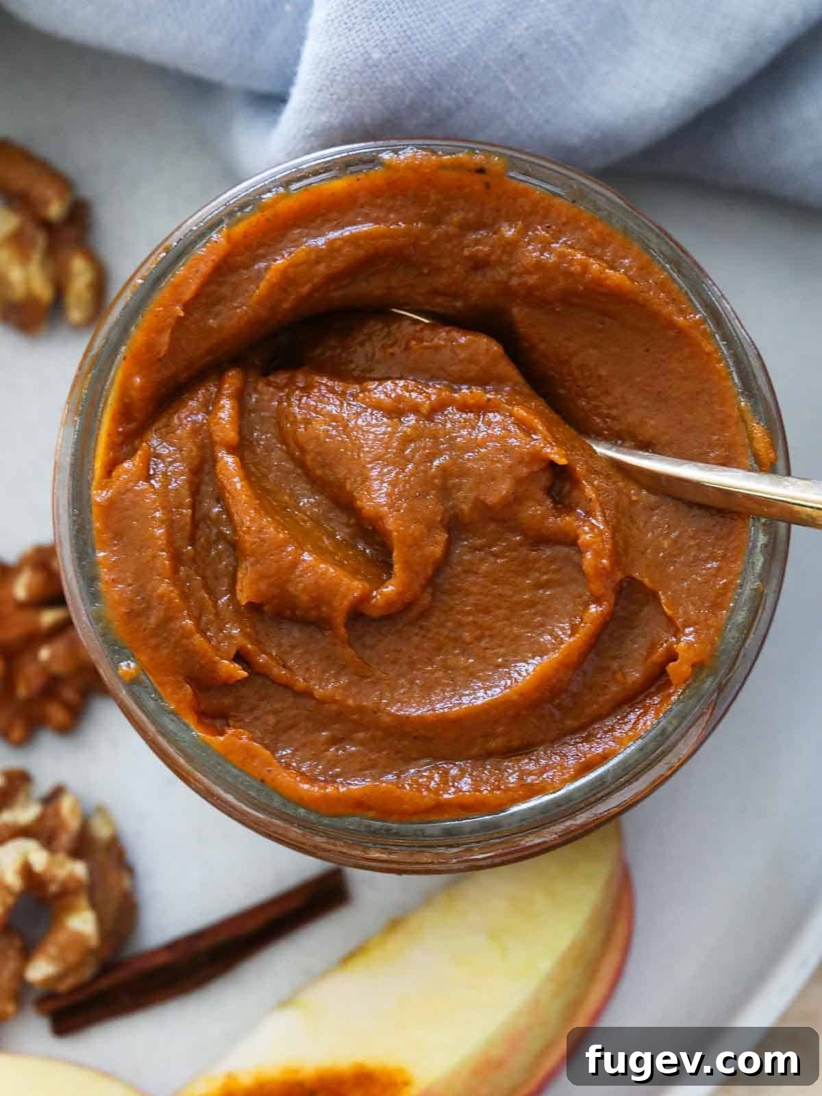 Cozy Spiced Pumpkin Butter 7 A spoon resting in a jar of homemade pumpkin butter, showcasing its rich, thick texture.