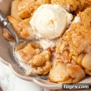 A scoop of vanilla ice cream melting deliciously on a warm slice of apple cobbler, a classic pairing.