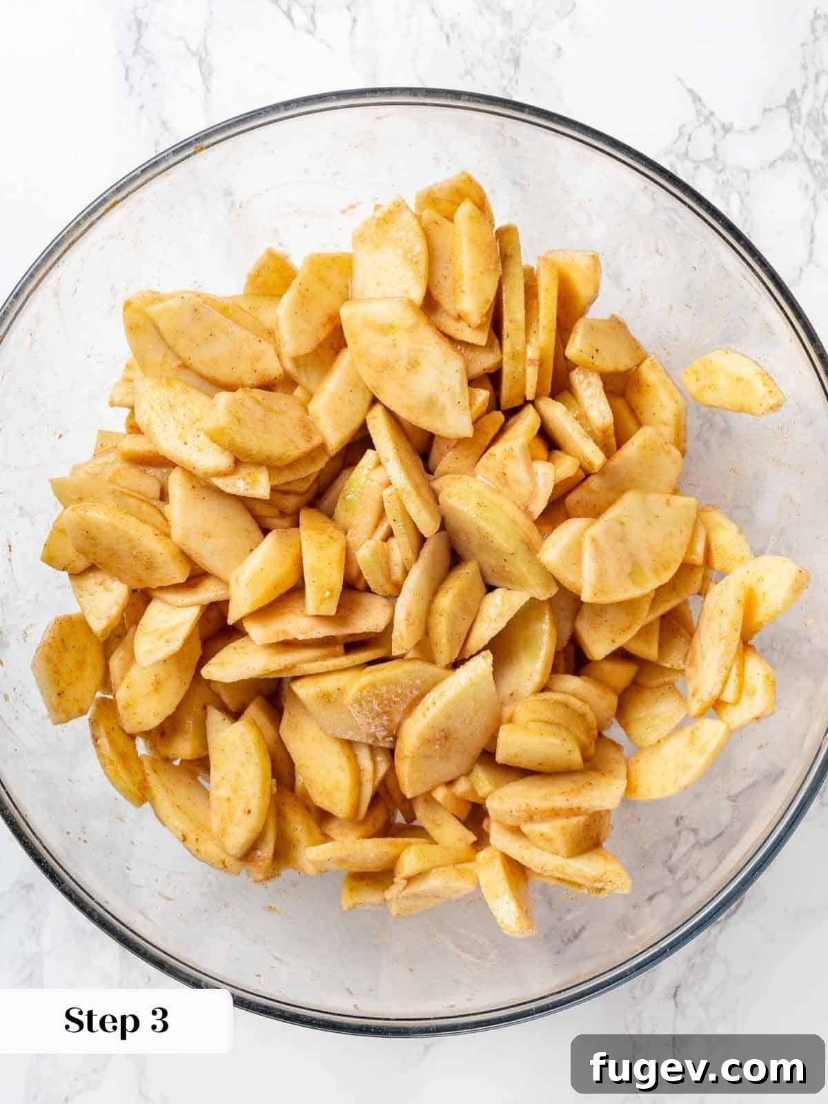 Cozy Apple Cobbler Magic 5 Freshly sliced apple pieces mixed with aromatic spices and a blend of sugars, ready for the cobbler filling, in a large mixing bowl.