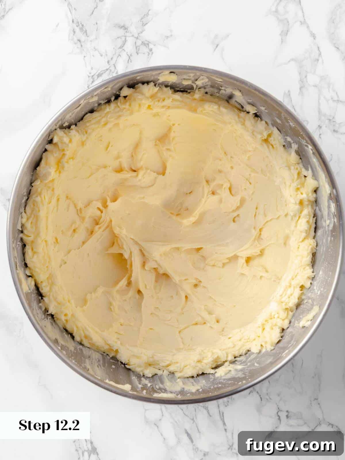 Frosting for the applesauce cake in a metal mixing bowl.